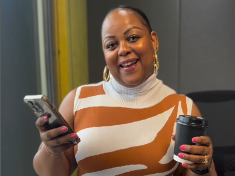 Carol Ofori standing inside the studio with a coffee and her phone