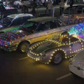 Cars parked next to one another draped in Christmas lights