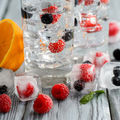 Cold cocktail with berries frozen in ice cubes