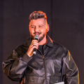 Danny Guselli speaking into a microphone on stage