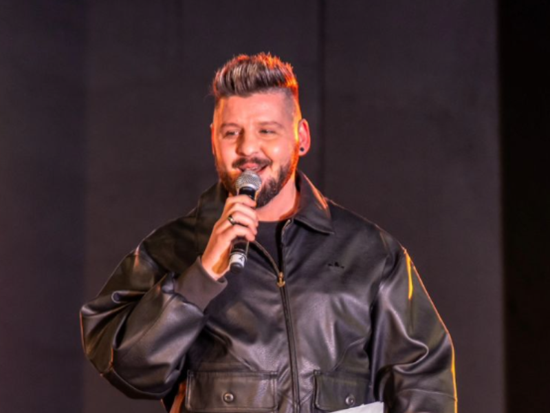 Danny Guselli speaking into a microphone on stage