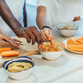 Kid and adults eat carrot sticks with hummus
