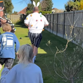 Kids run after their dads in the garden for an Easter egg hunt