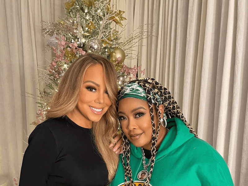 Mariah Carey and Da Brat pose next to a Christmas tree-min.png