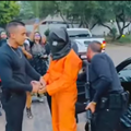 Men standing with a handcuffed person who looks like a prison inmate