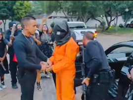 Men standing with a handcuffed person who looks like a prison inmate