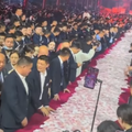 People standing along a long table decorated with heaps of cash