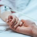 Recovering little child lying in the hospital holding mothers hands