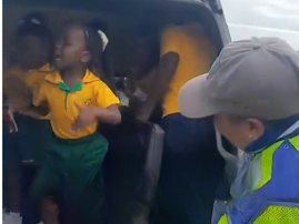 School kids dance inside a taxi while a traffic cop looks on
