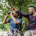 Couple sight seeing with binoculars in the forest