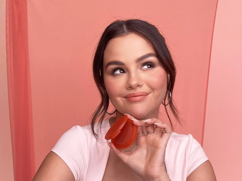 Selena Gomez poses in a studio with a pink background