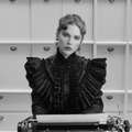 Taylor Swift sitting in front of a typewriter