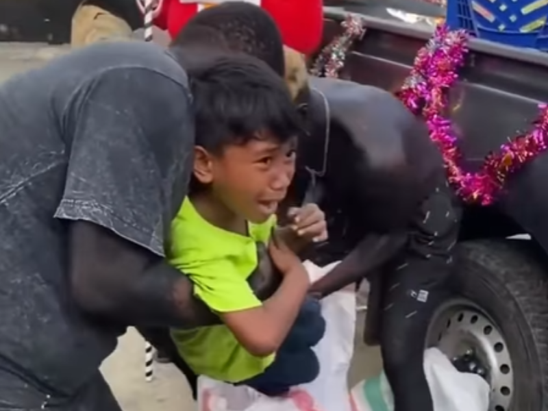 Two men pull a child away from his mother and try to put him inside a sack