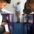 Two pupils playing with a phone in class