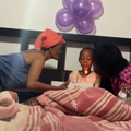 Two women lean in to kiss a young girl as she blows out her birthday candles