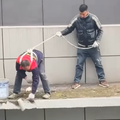 Two workmen on top of a building roof painting
