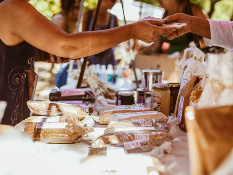 View of people at a Farmers market exchanging goods for money