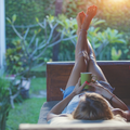 Woman relaxed on a garden sofa with her feet up