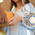 woman wearing a blue top accepts an orange package