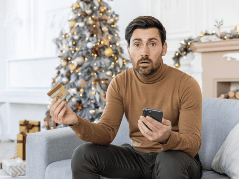 worried young man holding a credit card and phone